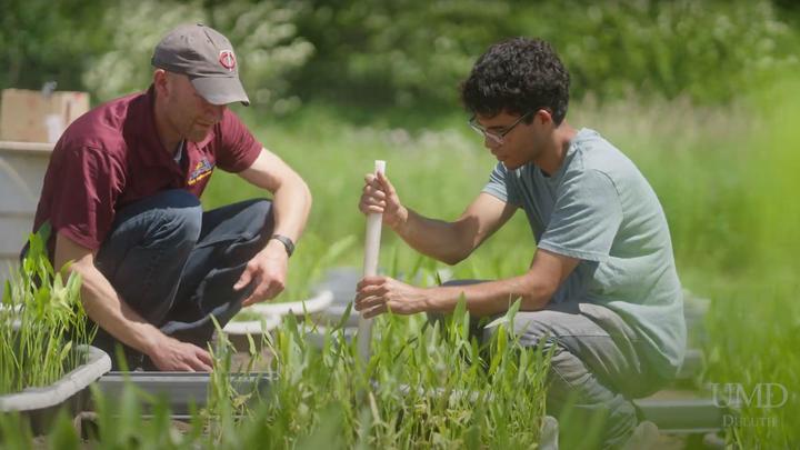 Nate Johnson and a student collect a sediment sample in their outdoor lab