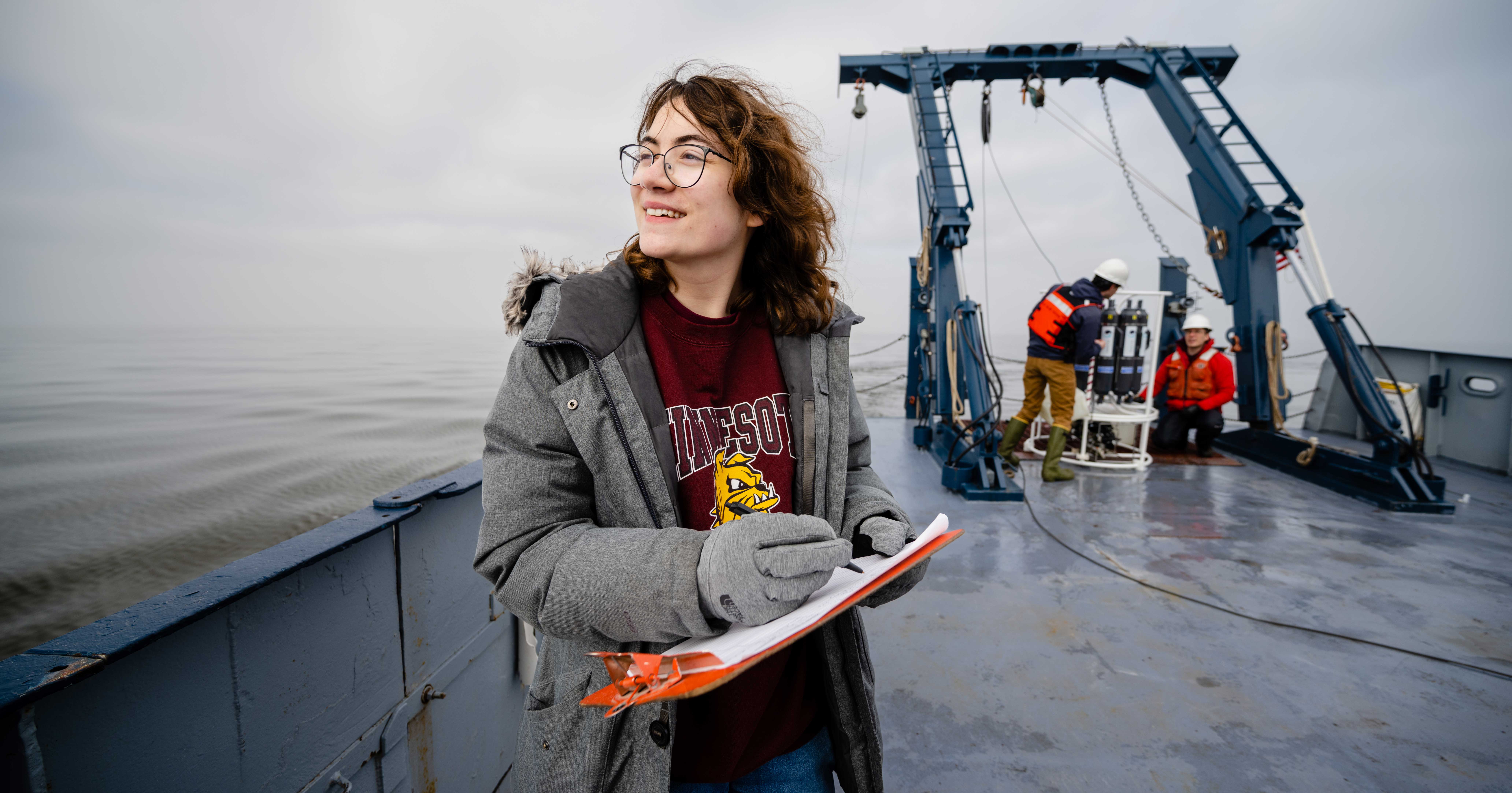Student on the deck of the research vessel Blue Heron with a clipboard