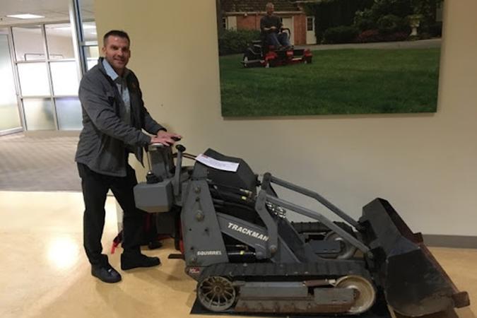 A photo of Dr. Michael Pluimer with a Toro Company Dingo machine