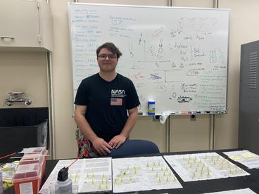 Meighan in front of a whiteboard showing his work