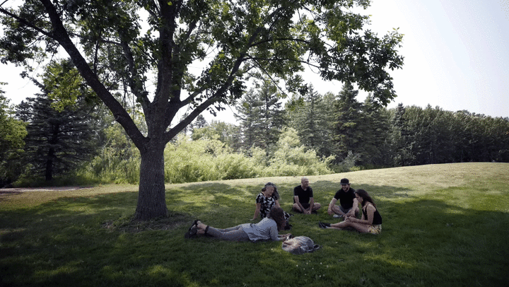 Julie Etterson and students talking under a shade tree on campus