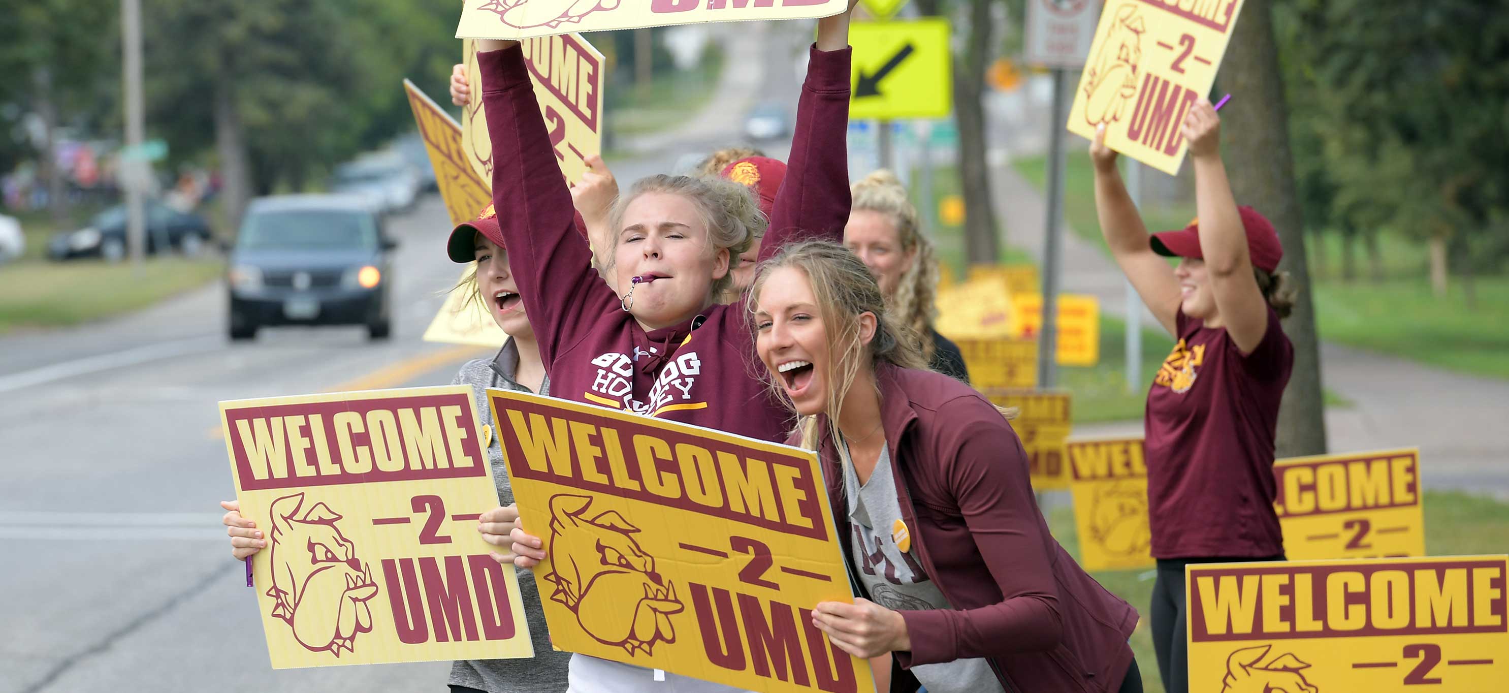 Students with Welcome Week signs
