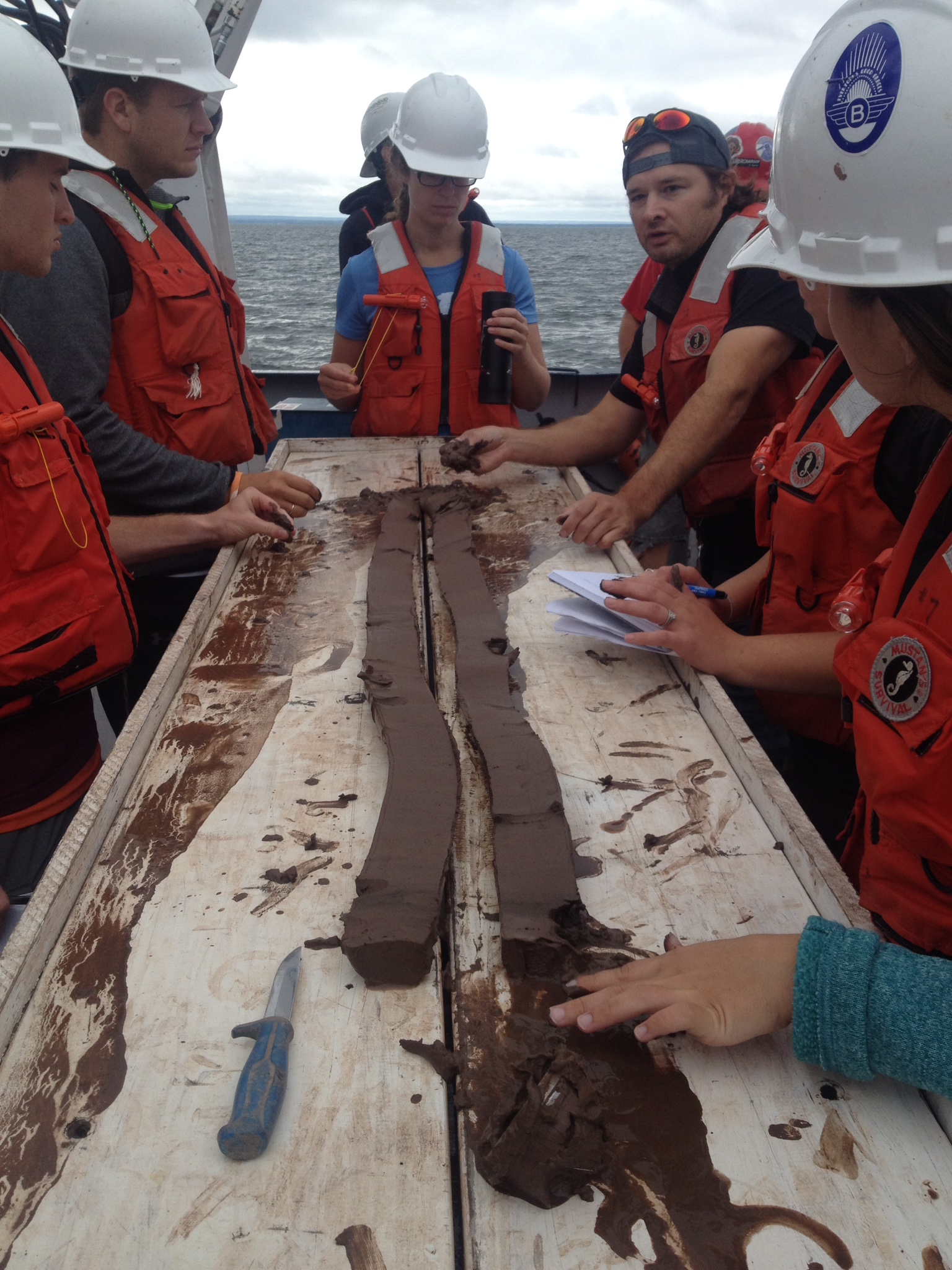 A field learning experience with professors and students gathered around a lake core
